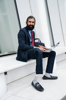 Businessman in a suit working on a laptop in a modern urban setting, displaying professionalism.