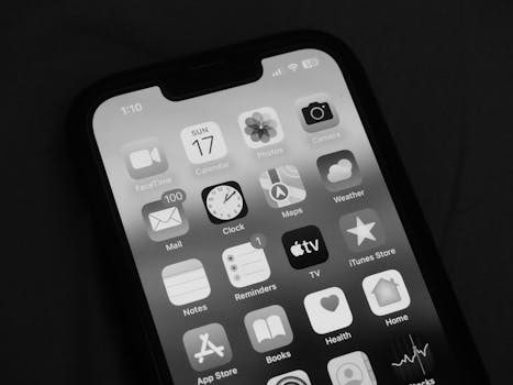Close-up of a smartphone screen showing various app icons in monochrome.