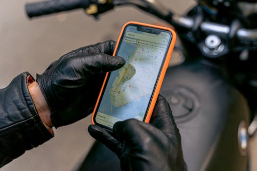 Motorcyclist with gloves using smartphone GPS navigation system while riding.