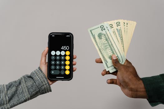 Two hands displaying cash and a smartphone calculator with a digital display, indicating a financial transaction.